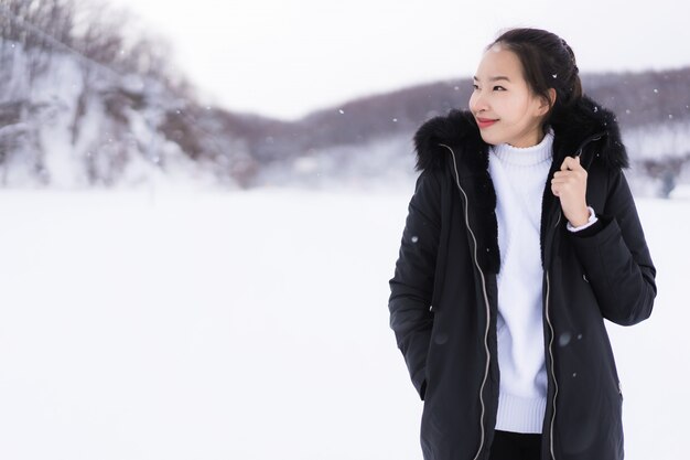Het mooie jonge Aziatische vrouw glimlachen gelukkig voor reis in sneeuw wintertijd