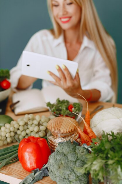 Het mooie meisje maakt een salade. Sportieve blondine in een keuken. Vrouw recept in notitieblok schrijven.