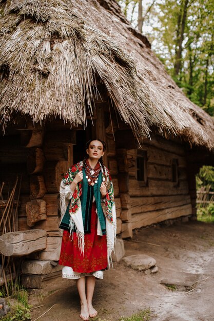 Het mooie meisje stelt op de binnenplaatsen dichtbij het huis in een traditionele Oekraïense kleding