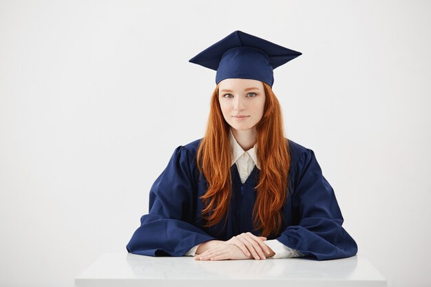 Het mooie roodharige vrouwelijke gediplomeerde glimlachen.