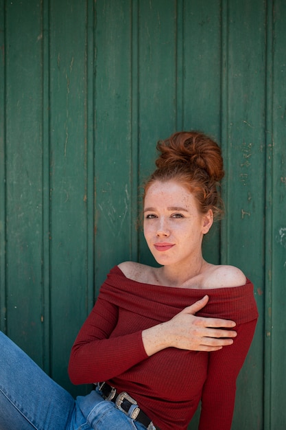 Gratis foto het mooie roodharigevrouw stellen met groene achtergrond