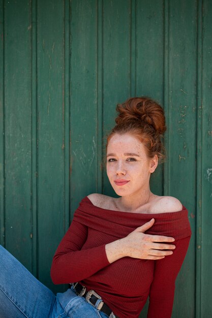 Het mooie roodharigevrouw stellen met groene achtergrond