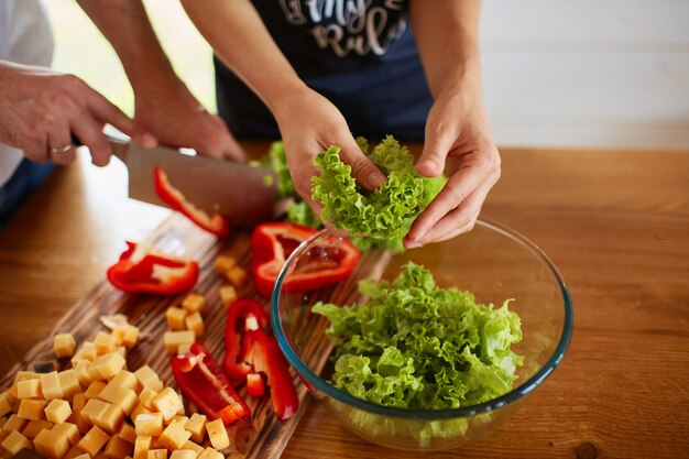 Het mooie verliefde paar snijdt een rode paÃ «r in de keuken