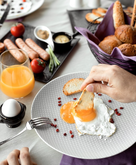 Het onderdompelen van de mens braadstuk in ei geel voor ontbijt