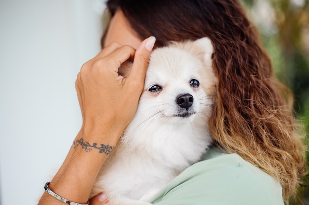 Het openluchtportret van krullende Europese gelooide vrouw houdt gelukkige spitz van Pommeren van de huisdierenhond