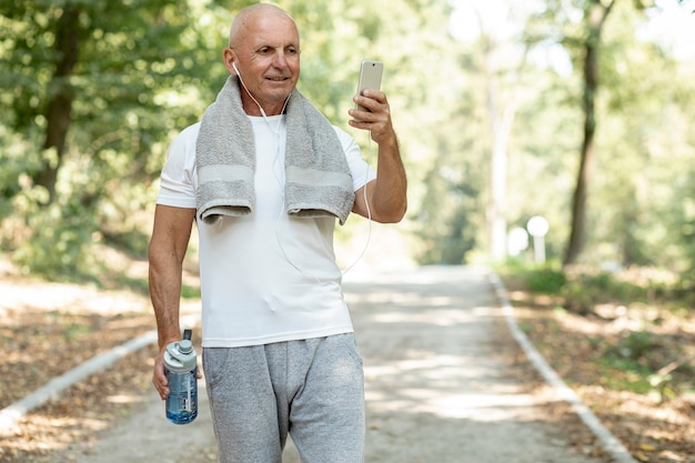 Het oudere rusten cheking zijn telefoon in het bos