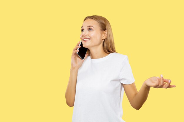 Het portret van de halve lengte van de Kaukasische jonge vrouw op gele studio