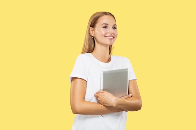 Het portret van de halve lengte van de Kaukasische jonge vrouw op gele studio