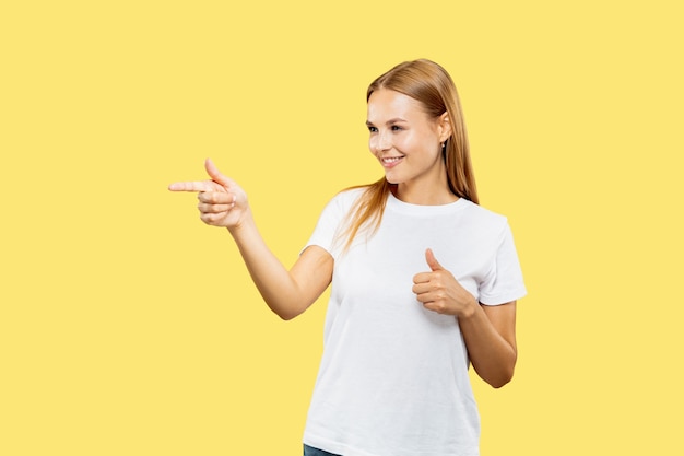 Het portret van de halve lengte van de Kaukasische jonge vrouw op gele studio