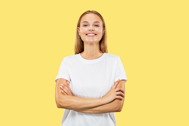 Het portret van de halve lengte van de Kaukasische jonge vrouw op gele studio