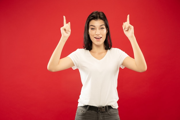 Het portret van de halve lengte van de kaukasische jonge vrouw op rode studio