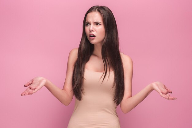 Het portret van de jonge vrouw met droevige emoties op roze studio