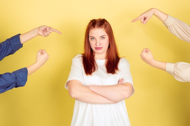 Het portret van de kaukasische jonge vrouw op gele studio