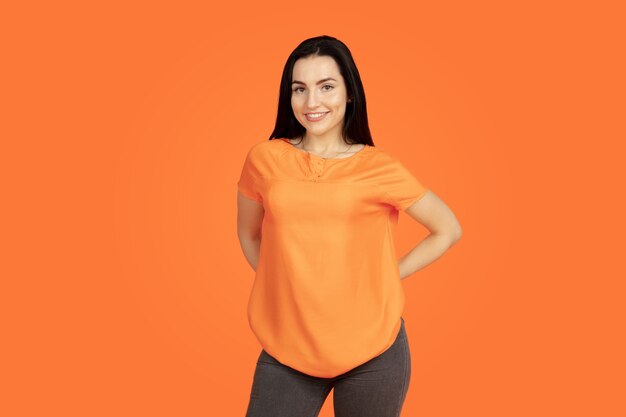 Het portret van de Kaukasische jonge vrouw op oranje studio