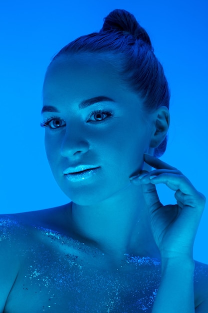 Gratis foto het portret van de knappe die vrouw op blauwe studioachtergrond in zwart-wit neonlicht wordt geïsoleerd. mooi vrouwelijk model. concept van menselijke emoties, gezichtsuitdrukking, verkoop, advertentie, mode en schoonheid.