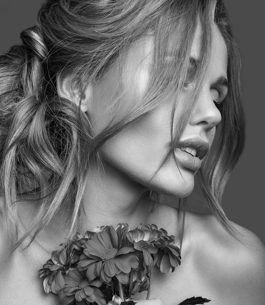 Gratis foto het portret van de schoonheidsmanier van jong blond vrouwenmodel met natuurlijke make-up en perfecte huid met het heldere bloemen stellen