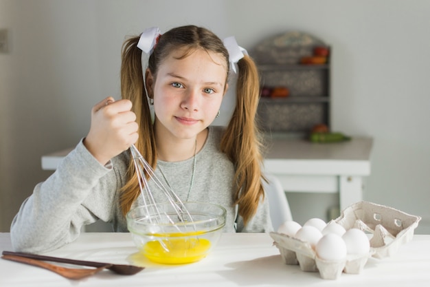 Gratis foto het portret van een meisje die de eierdooier mengen met zwaait