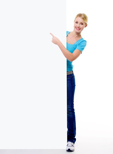 Het portret van gemiddelde lengte van een Mooie blonde vrouwelijke persoon wijst op het lege aanplakbord - dat op wit wordt geïsoleerd