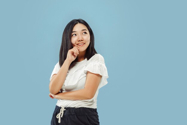 Het portret van halve lengte van de Koreaanse jonge vrouw op blauw