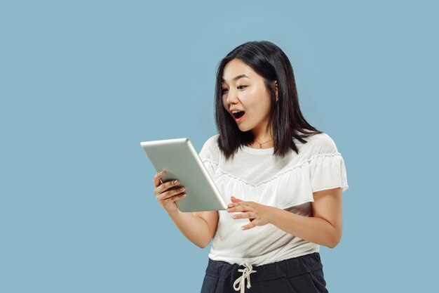 Het portret van halve lengte van de Koreaanse jonge vrouw op blauwe achtergrond