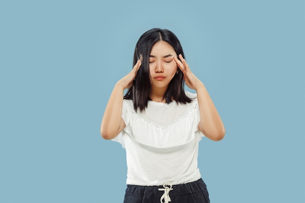 Het portret van halve lengte van de Koreaanse jonge vrouw op blauwe achtergrond