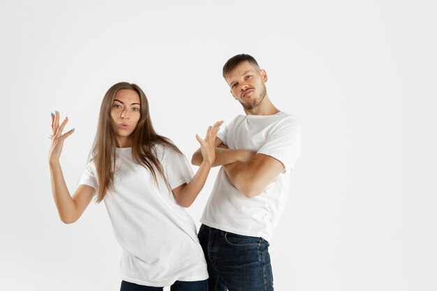 Het portret van het mooie jonge paar dat op witte studioachtergrond wordt geïsoleerd. Gelaatsuitdrukking, menselijke emoties, reclameconcept. Copyspace. Vrouw en man die elkaars handen kruisen of dansen, zien er cool uit.