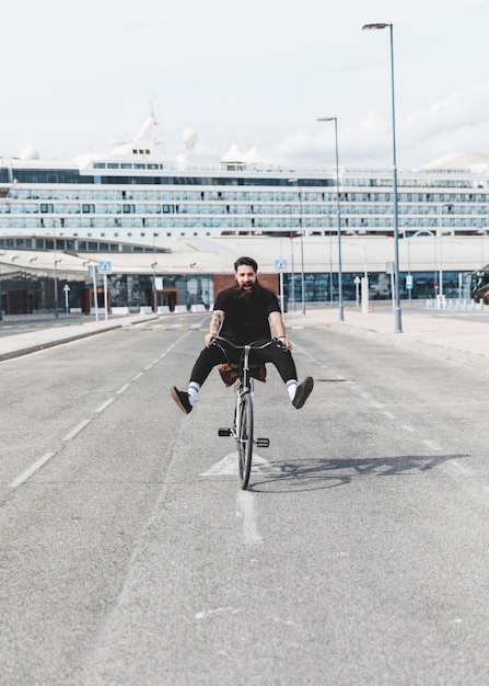 Het portret van jonge personenvervoerfiets op weg met benen schopte uit voor cruise