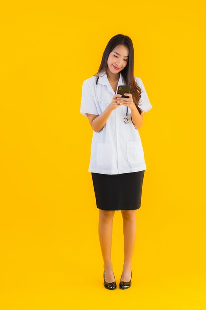 Het portret van mooie jonge Aziatische artsenvrouw gebruikt smartphone