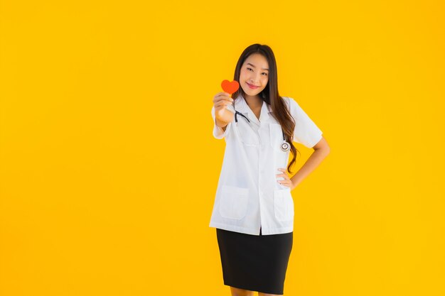 Het portret van mooie jonge Aziatische artsenvrouw toont rood hart