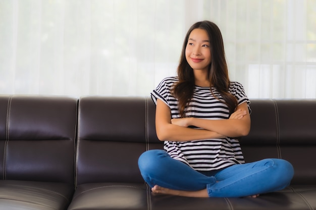Het portret van mooie jonge Aziatische vrouw ontspant op bank in woonkamer