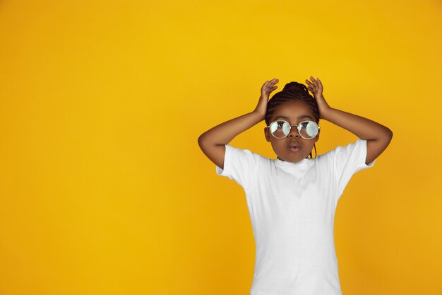 Het portret van weinig Afrikaans-Amerikaans meisje dat op gele studio wordt geïsoleerd