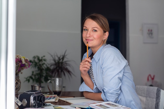 Gratis foto het potlood van de vrouwenholding en het stellen bij bureau