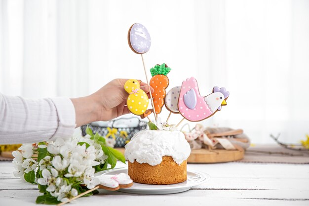 Het proces van het versieren van een feestelijke cake met peperkoek en bloemen. Het concept van de voorbereiding op de paasvakantie.