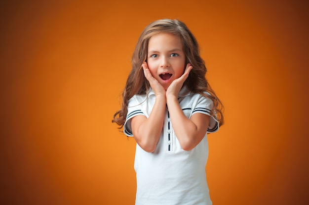 Het schattige verrast meisje op oranje muur