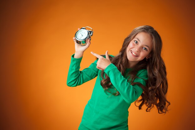 Het schattige vrolijke meisje op oranje muur