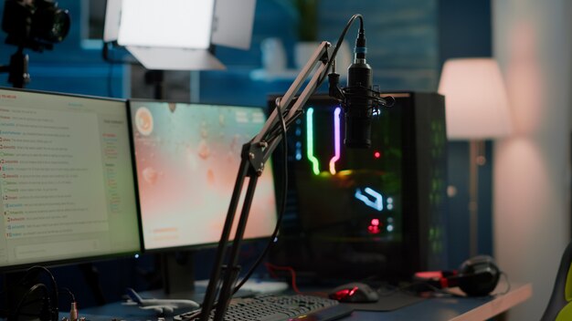 Het spel is voorbij op het display van een professionele krachtige RGB-computer en de streamchat is voorbereid op een virtueel toernooi. Streaming professionele microfoon in lege gaming-thuisstudio met neonlichten.