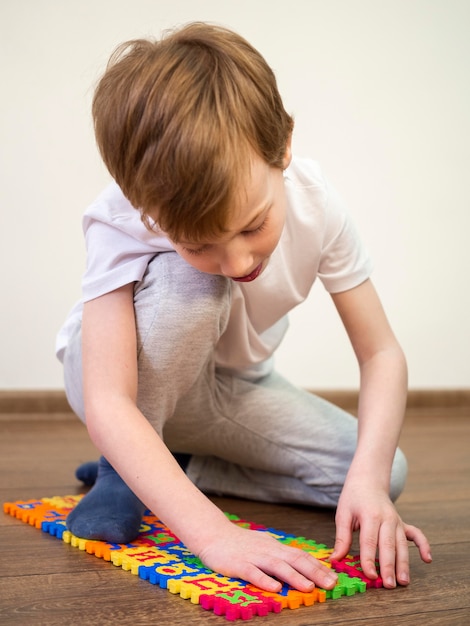 Het spelen van de jongen met alfabetspel op de vloer