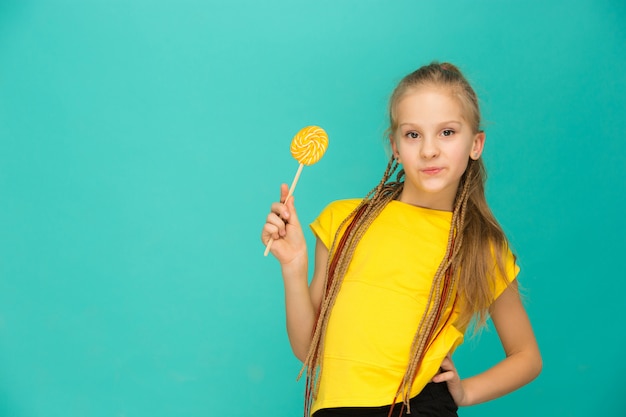 Het tienermeisje met kleurrijke lolly op een blauw