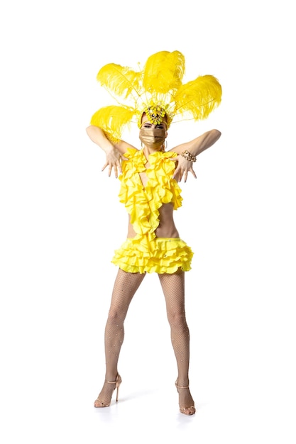 Het uitvoeren van. Mooie jonge vrouw in Carnaval-maskeradekostuum met gele veren die op witte achtergrond dansen. Concept van vakantieviering, feestelijke tijd, dans, feest, geluk. Copyspace