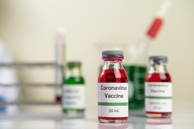 Het vaccin tegen de covid-19 is in rood en groen in flessen die op de grond zijn geplaatst.