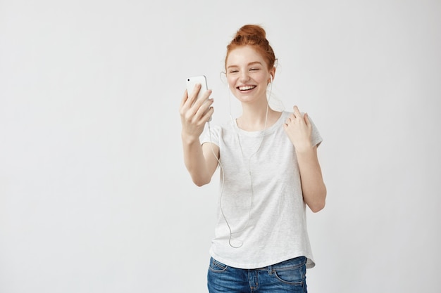 Het vrolijke foxy vrouw glimlachen die op telefoon in hoofdtelefoons spreekt.