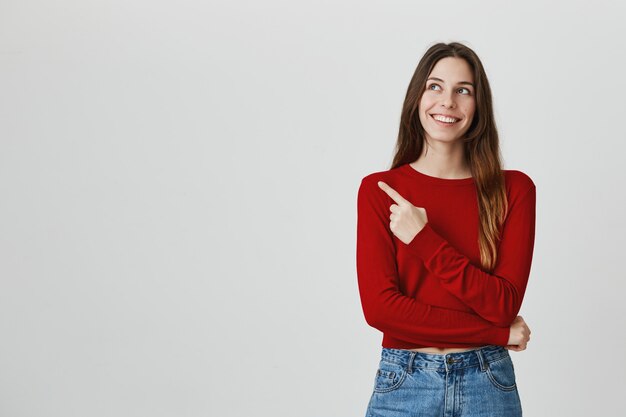 Het vrolijke het glimlachen mooie vrouw richten, die linkerbovenhoek reclame bekijken