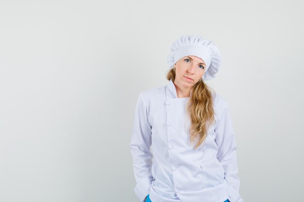 Het vrouwelijke chef-kok stellen met dient zakken in wit uniform in en ziet er schattig uit.