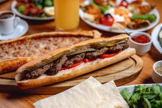 Het witte brood van de zijaanzichtsandwich met de verse tomaat van vleeskoteletten en ingelegde komkommer op een raad