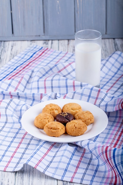 Het zijaanzicht van koekjes op een witte plaat diende met een glas melk