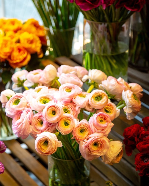 Het zijaanzicht van roze ranunculus bloeit boeket in glasvaas bij bloemenwinkel