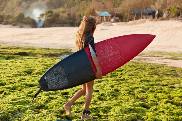 Gratis foto het zijdelings schot van professionele goofy draagt surfplank met leiband