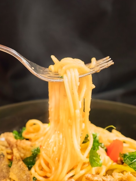 Hete en kruidige spaghetti met vork over zwarte achtergrond