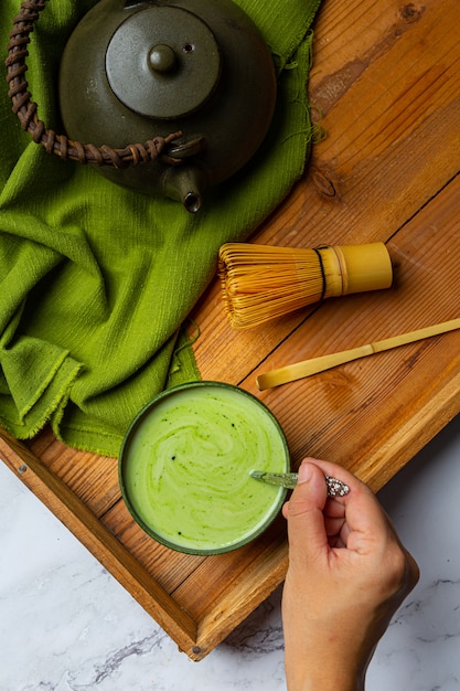 Gratis foto hete groene thee in een glas met room gegarneerd met groene thee, gedecoreerd met groene theepoeder.