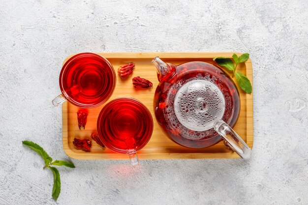 Hete Hibiscus thee in een glazen mok en glazen theepot.